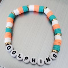 This Is A Miami Dolphins Beaded Bracelet In The Dolphins Colors Aqua, Orange And White. A Fun Bracelet To Wear Alone Or Stacking With Other Bracelets. These Bracelets Are Made With A Sturdy Elastic Cord Available In Multiple Sizes. Unisex Bracelets Size Guide: 5” - Kids 6” - Small 7” - Average Adult 8” - Large Thank You For Visiting My Store. Small Business Bracelet, Inspo Bracelets, Sea Beads, Make Clay Beads, Small Bead Bracelet, Pony Bead Bracelets, Clay Bracelets, Clay Bead Necklace, Beaded Braclets