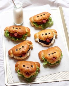 there are many sandwiches shaped like dogs on a tray next to a glass of milk