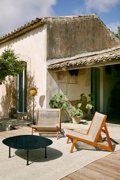 a patio with two chairs and a table on the ground next to an outdoor living area