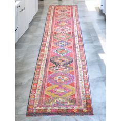 a long, colorful runner rug in the middle of a kitchen