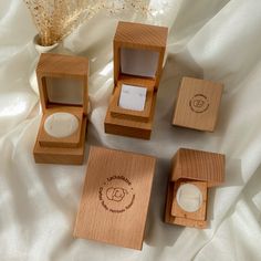 four wooden boxes with rings inside sitting on a white cloth