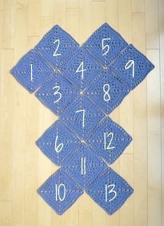 a blue crocheted rug with numbers and times on it sitting on a wooden floor