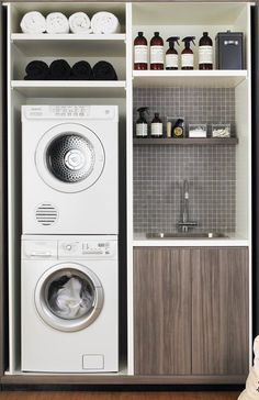 a washer and dryer in a small room next to a shelf filled with bottles