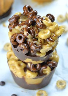 two chocolate cups filled with cereal and pretzels on top of eachother