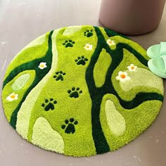 a green rug with paw prints on it next to a potted plant and other items