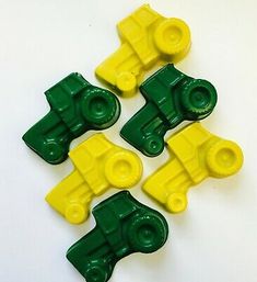 four yellow and green lego pieces sitting on top of a white table next to each other