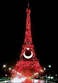 the eiffel tower is lit up in red and white lights for christmas time