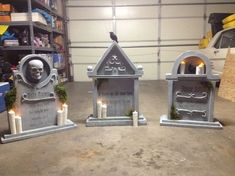 three cement tombstones with candles in them and a skull on the top, sitting next to each other