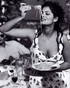 a woman is eating spaghetti from a plate