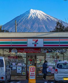 cars are parked in front of a store with a mountain in the backgroud