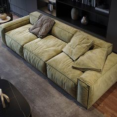 a large green couch sitting on top of a wooden floor next to a book shelf