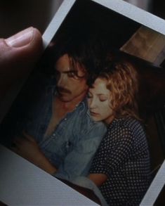 a person holding a polaroid with an image of a man and woman on it