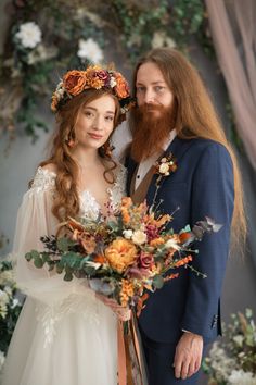 a bride and groom posing for a photo with flowers in their hair, dressed in blue suit