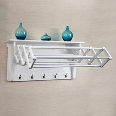 a white shelf with three blue vases on it and two hooks in the middle