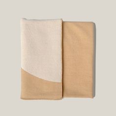 two towels folded on top of each other in beige and white colors, one with an orange stripe