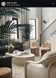 a living room filled with furniture next to a stair case and potted palm tree