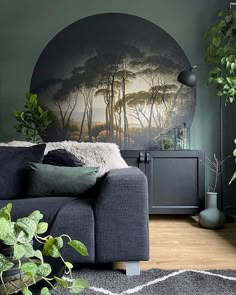 a living room with green walls and a black couch in front of a painting on the wall