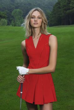 a woman in a red dress is holding a golf club and posing for the camera