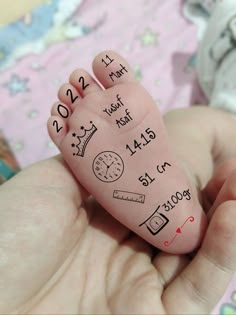 a baby's hand with writing on it and numbers written on the fingers that read 2012