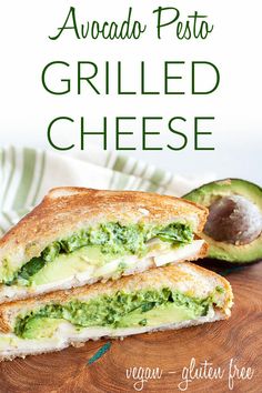 a grilled cheese sandwich cut in half on a cutting board with avocado