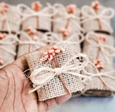 a hand holding a small piece of brown paper wrapped in burlock and tied with twine