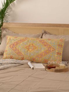 the bed is made with an orange and yellow decorative pillow on it's side