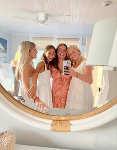 three women taking a selfie in front of a mirror