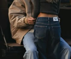 a person sitting on a bench with their back to the camera, wearing jeans and a jacket