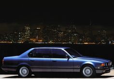 a blue car parked in front of a city at night