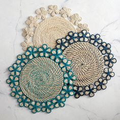 three woven coasters with blue and white designs on marble counter top, one is circular