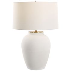 a white table lamp with a beige shade on the bottom and gold trim around the base