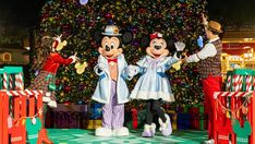 mickey and minnie mouse characters standing in front of a christmas tree at disneyland's hollywood studios