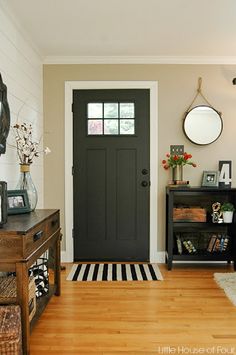 a living room with a black door and white walls, wood floors and rugs on the floor