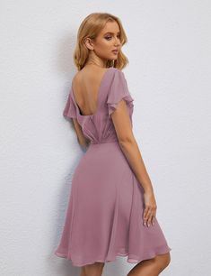 a woman in a purple dress leaning against a wall with her back to the camera