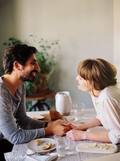 a man and woman sitting at a table with food