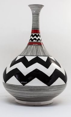 a black and white striped vase with red accents on the top, sitting in front of a white background