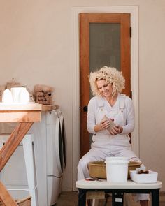 a woman sitting on top of a table in front of a washing machine