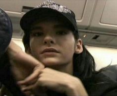 a young woman wearing a hat and sitting on an airplane with her arm around the seat