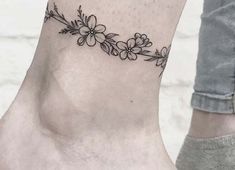 a woman's foot with a flower tattoo on the side of her leg and ankle