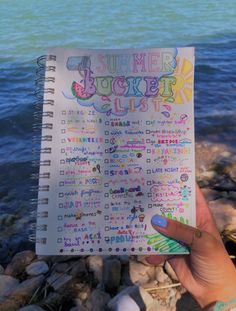 a person holding up a planner with the words summer bucket list written in front of them