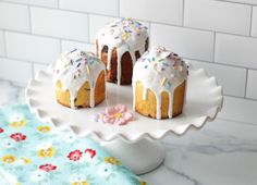 three bundt cakes with white frosting and sprinkles on a cake plate