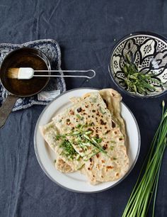 some food is sitting on a white plate and next to two bowls with spoons