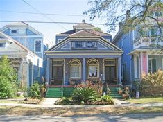 a house with blue siding and green steps in front of it on a street corner