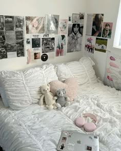 a white bed topped with lots of pillows and stuffed animals next to a laptop computer