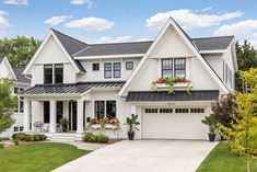 a large white house with black roof and two car garages on the front porch