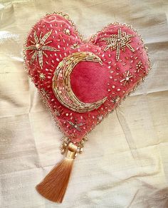 a heart shaped pillow with a tassel hanging from it