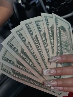 a woman's hand holding money in her left hand and nails on the other