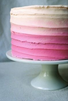 a cake with pink and white frosting sitting on top of a cake platter