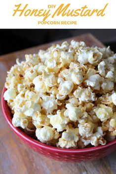 a red bowl filled with popcorn on top of a wooden table