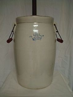 a large white vase sitting on top of a white cloth covered floor next to a wooden stick